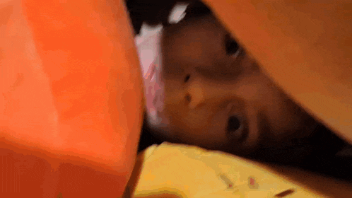 a baby is laying under a blanket on a bed .