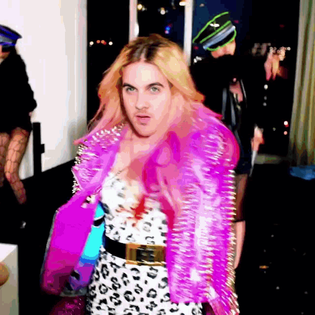 a woman in a leopard print dress is wearing a pink jacket with spikes on it