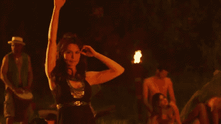 a woman in a black dress is dancing in a dark room with a group of people .