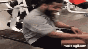 a man is smiling while sitting on a bench in a gym