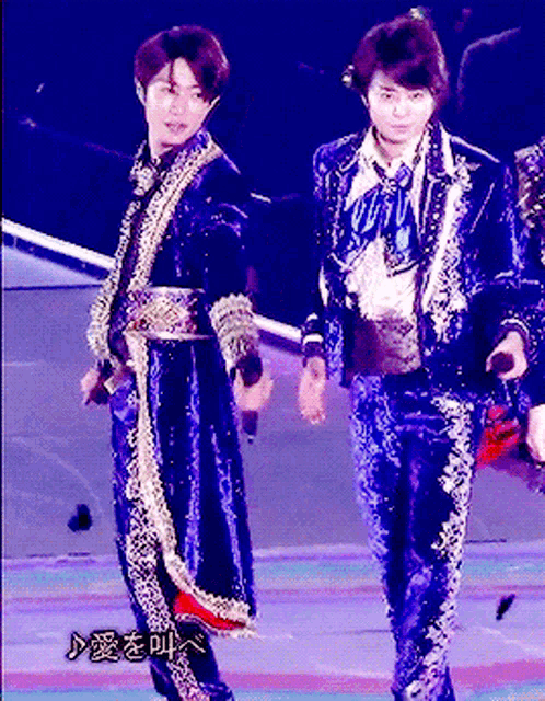 a man in a blue suit stands next to another man in a blue suit