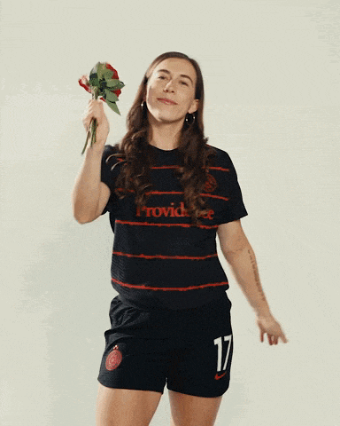 a woman wearing a black providence shirt holds a bouquet of roses