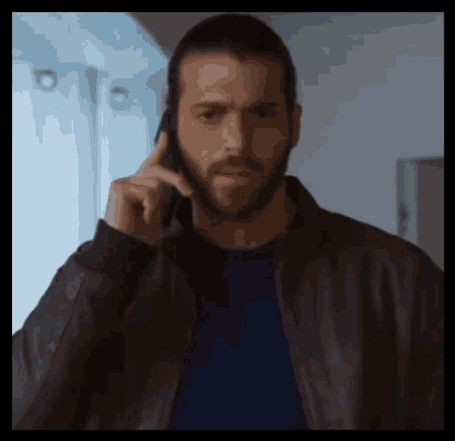 a man with a beard is talking on a cellphone