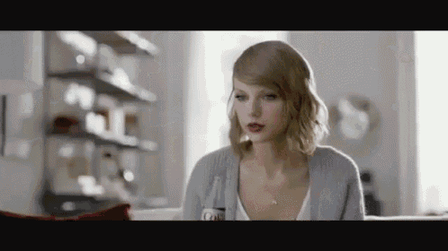 taylor swift is sitting on a couch holding a bottle of coke .