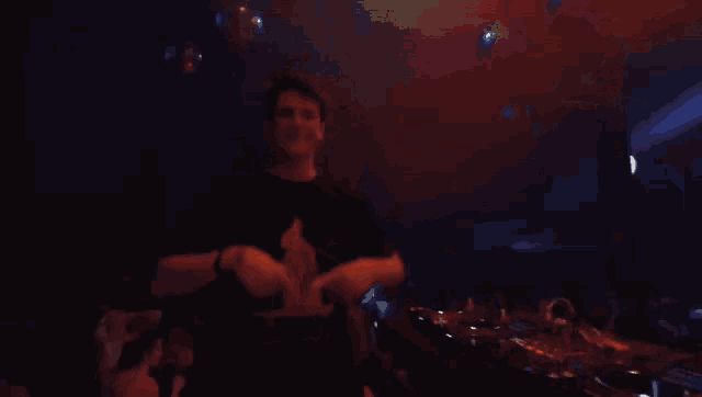 a man in a black shirt is playing a dj set in a dark room