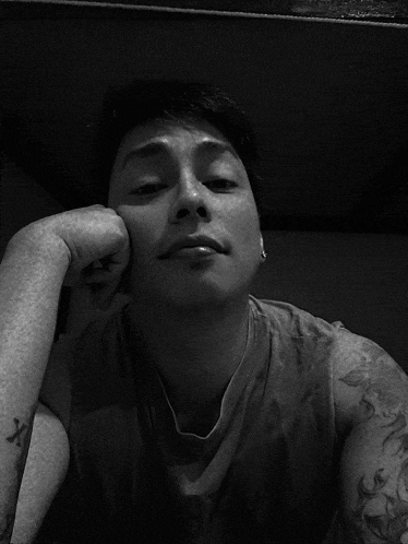 a man with a tattoo on his arm rests his hand on his face