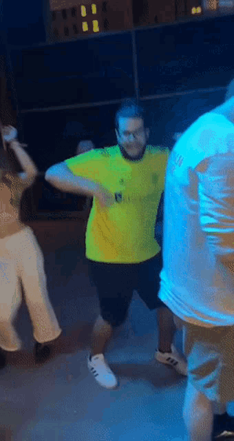 a man in a yellow adidas shirt is dancing with another man