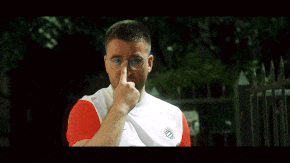 a man wearing glasses and a white and red nike shirt looks at the camera
