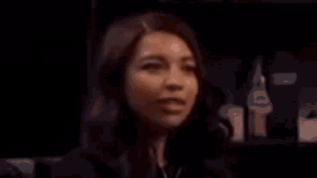 a woman is making a surprised face in a dark room while wearing a bracelet .