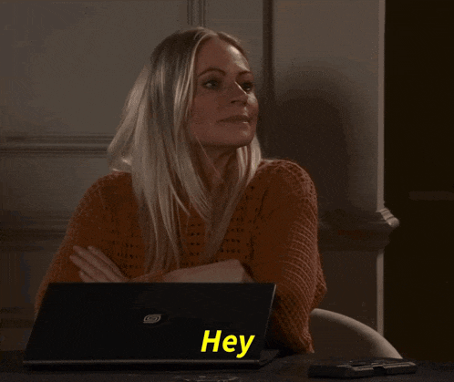 a woman sits in front of a laptop that says hey on it