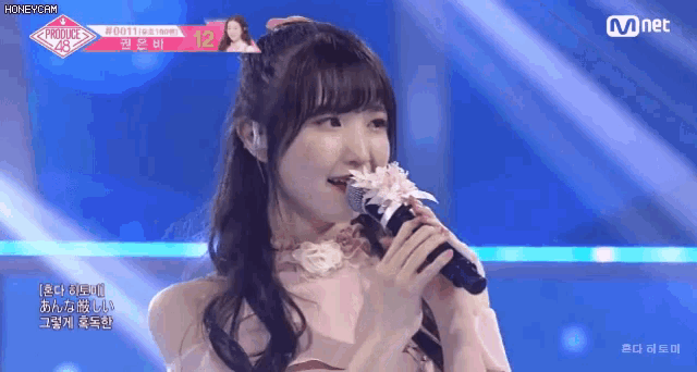 a girl singing into a microphone with the number 12 on the top right