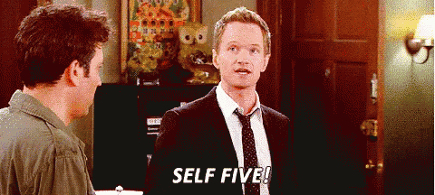a man in a suit and tie says self five while standing next to another man