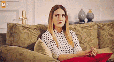a woman is sitting on a couch with a pillow on her lap .