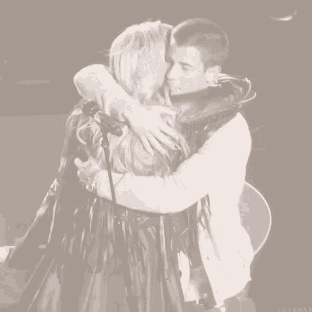 a black and white photo of a man and a woman hugging with the word lovanas on the bottom