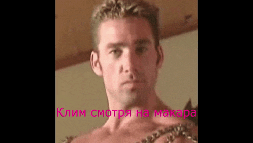 a shirtless man is wearing a chain around his neck and looking at the camera .