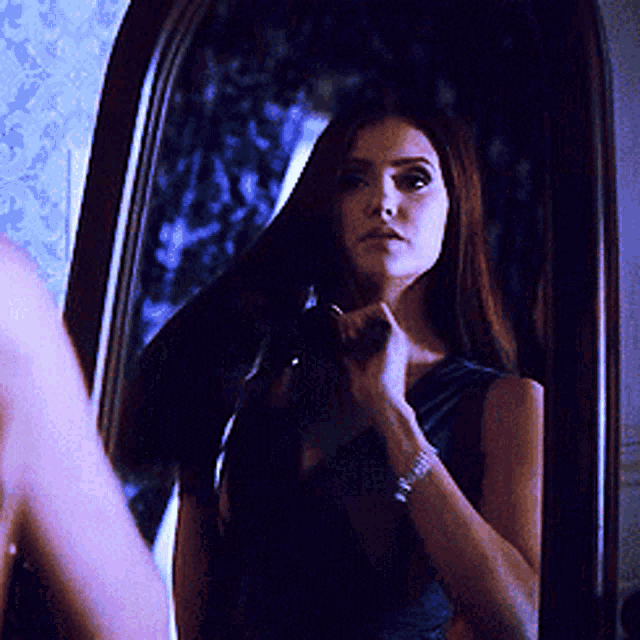 a woman is looking at herself in a mirror