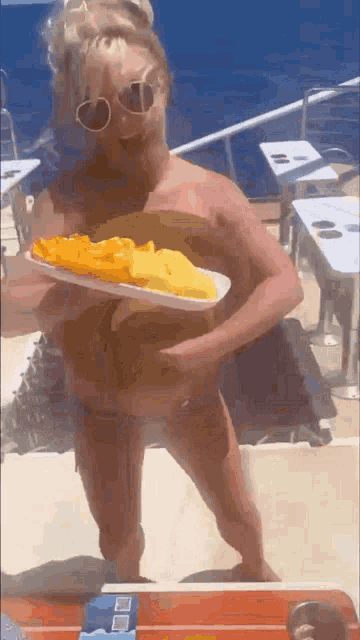 a woman in a bikini is holding a tray with food on it