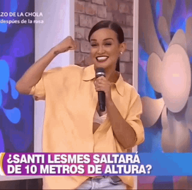 a woman in a yellow shirt is holding a microphone and smiling