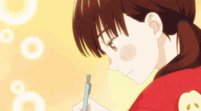 a girl in a red shirt is writing on a piece of paper with a pen