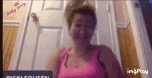 a woman in a pink tank top is smiling in front of a sign that says dicki queen