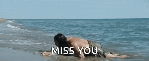 a man is laying in the water on the beach with the words `` miss you '' written on the bottom .