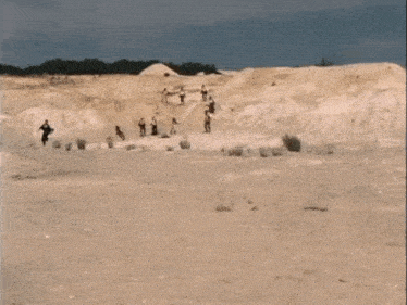 a group of people are running in the sand in a desert .