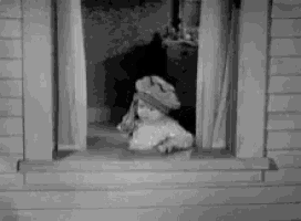 a black and white photo of a child looking out a window .
