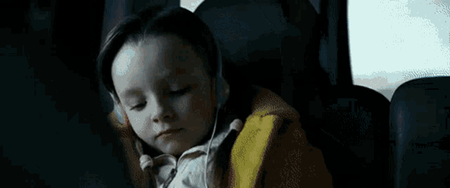 a young girl wearing headphones is sitting in a car seat .