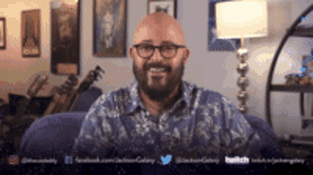 a man with glasses and a beard is smiling in a living room
