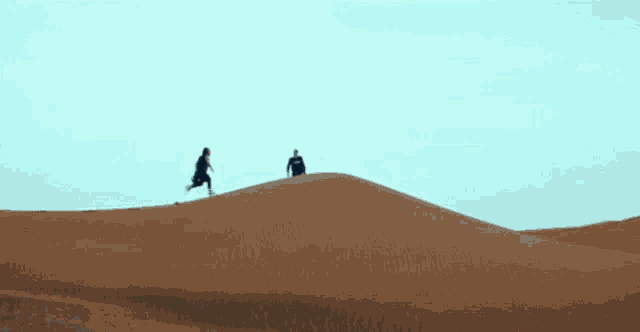 a man is standing on top of a sand dune while a bird flies overhead