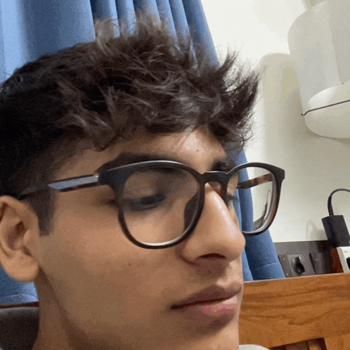 a young man wearing glasses is looking at the camera