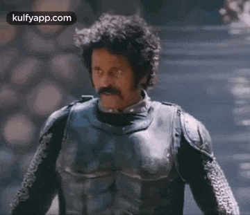 a man with a mustache is wearing armor and a sword .