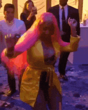 a woman with pink hair and a yellow jacket is dancing in a room .