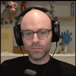 a bald man wearing glasses and headphones is looking at the camera .