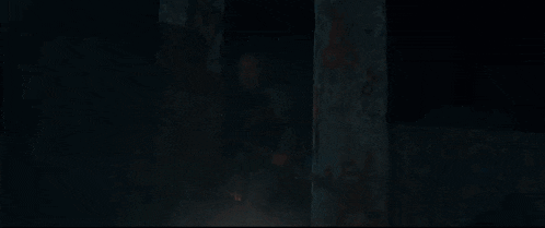 a man is sitting in a dark room with a fire in the background .