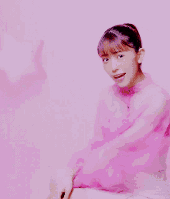 a girl in a pink dress is sitting in front of a pink wall