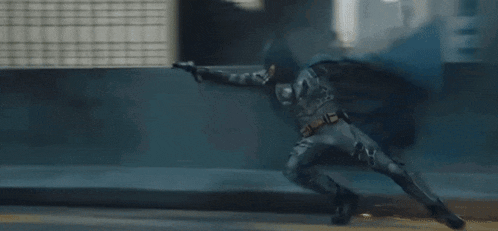 a man in a batman costume is flying over a bridge