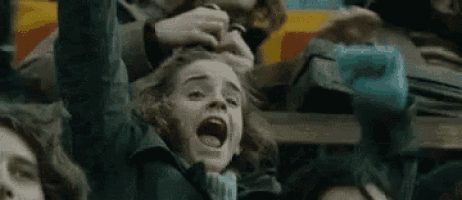 a group of people are sitting in a stadium with their arms up in the air .