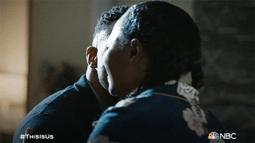 a close up of a man and woman hugging with the nbc logo in the background