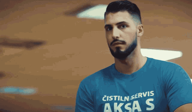 a man with a beard wearing a blue shirt that says cistil servis