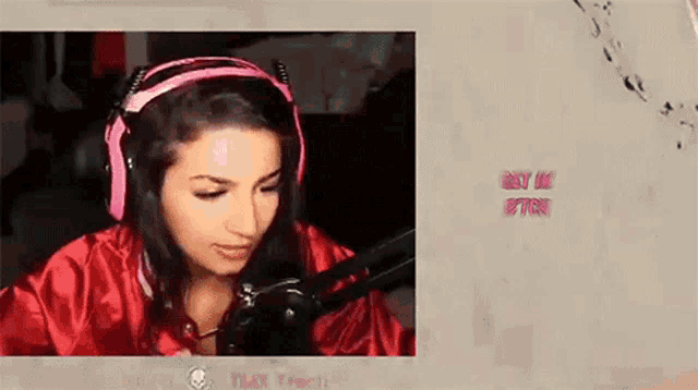 a woman wearing headphones and a red jacket is sitting in front of a microphone ..