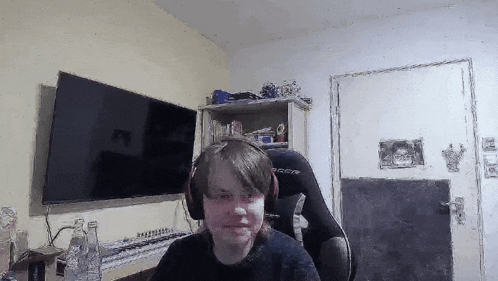 a young man wearing headphones is sitting in a chair in front of a television .