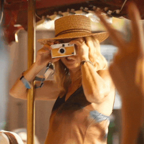 a woman in a straw hat takes a picture with a small camera