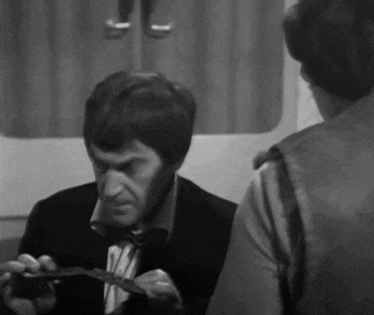 a man in a suit and tie is holding a piece of paper and talking to another man