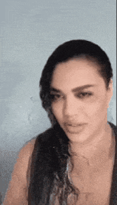 a woman with long black hair is making a funny face while wearing a black tank top .