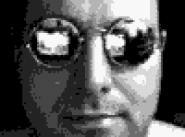 a black and white photo of a man wearing sunglasses and looking at the camera .