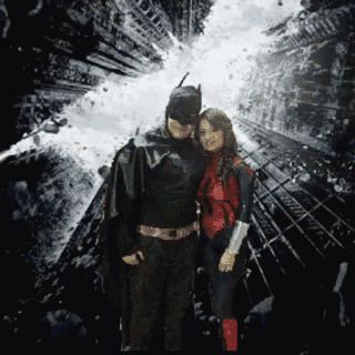 a man in a batman costume stands next to a woman in a spiderman costume
