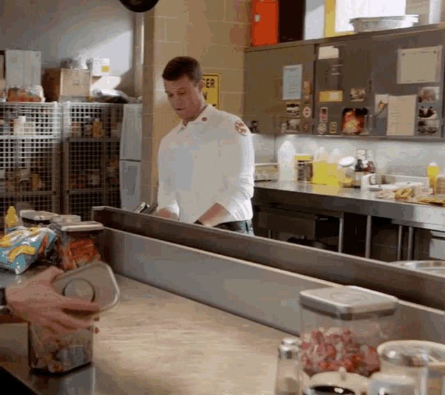 a man in a white uniform is standing in a kitchen with a yellow sign that says er on it