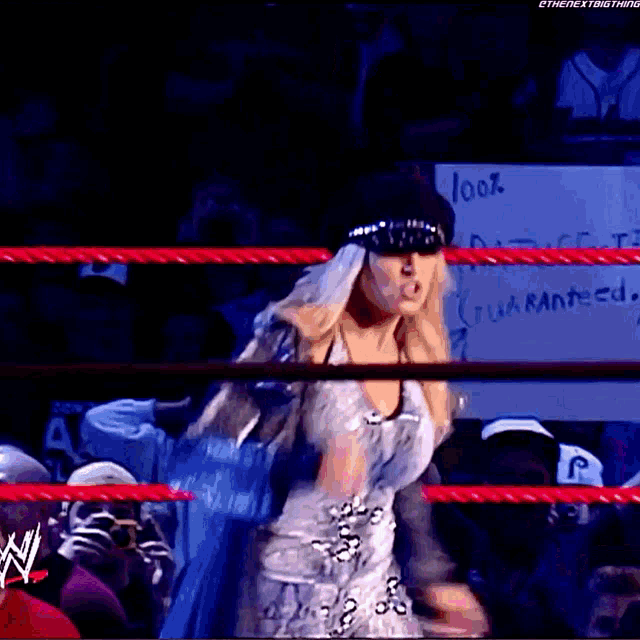 a woman is standing in a wrestling ring with a sign behind her that says look guaranteed