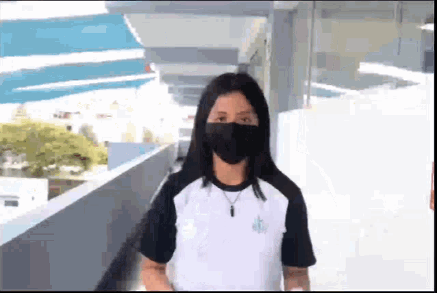 a girl wearing a black mask and a white shirt with the letter a on the front